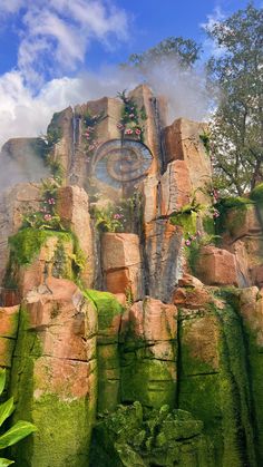 a large rock formation with a clock on it's face surrounded by greenery