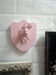 a pink deer head mounted to the side of a white brick wall