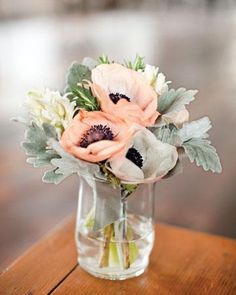 an arrangement of flowers in a glass vase on a wooden table with blurry background