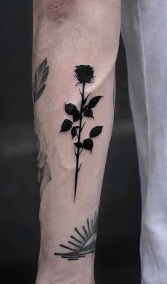 a black rose tattoo on the left forearm