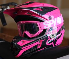 a pink and black helmet sitting on top of a table next to a pair of glasses