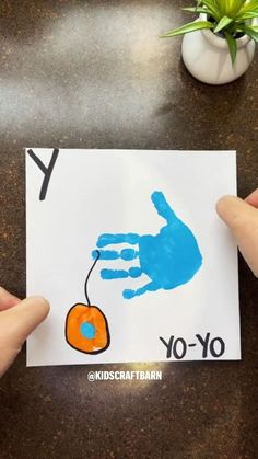 two hands holding up a handprinted card with the letter y to yo - yo