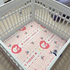 a white crib with a pink and red baby quilt in the middle, next to a stuffed animal