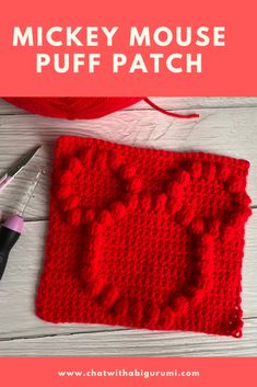 a red crocheted square with the words mickey mouse puff patch on it next to a pair of scissors