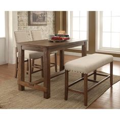 a dining room table with two stools and a place setting on the rug in front of it