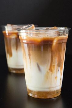 two glasses filled with dessert sitting on top of a black table next to each other