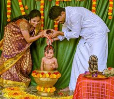 a man and woman standing next to a baby in a bowl with flowers on it