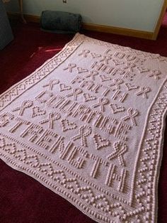 a white crocheted blanket sitting on top of a red carpet next to a couch