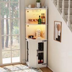 a small white cabinet with wine bottles in it next to a stair case that leads up to the second floor