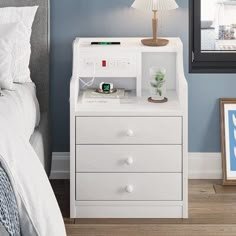 a bedroom with blue walls, white furniture and a lamp on the nightstand next to it