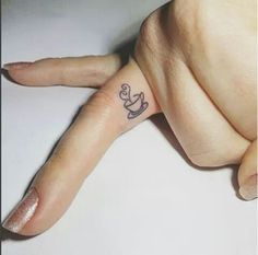 a person's hand with a small tattoo on the middle finger and an anchor in the middle