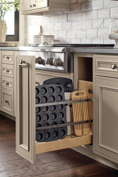 an open cabinet in a kitchen with utensils and cutting boards on the bottom drawer