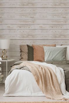 a bed with pillows and blankets on it in front of a wooden paneled wall