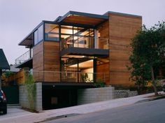 a car is parked in front of a modern house with wood sidings and balconies