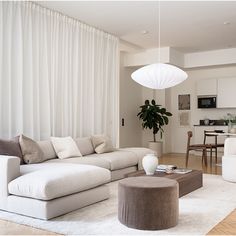 a living room filled with furniture and a large white curtained window behind the couch