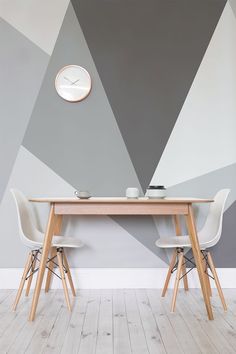 two white chairs sitting at a table with a clock on the wall behind it in front of them