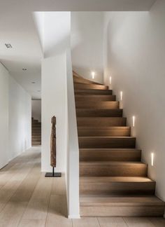 there is a very long staircase with some lights on the wall and wood flooring