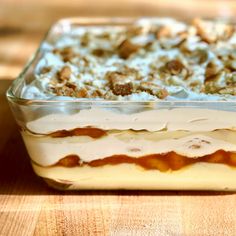 a casserole dish is sitting on a wooden table with white frosting and toppings