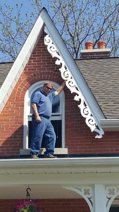 a man standing on top of a roof with his hand in the window sill