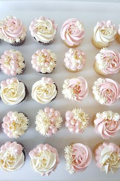 cupcakes with pink and white frosting are arranged in rows on a tray