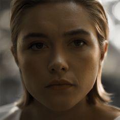 a close up of a person wearing a white shirt and looking at the camera with a serious look on her face