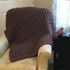 a brown crocheted blanket sitting on top of a white chair