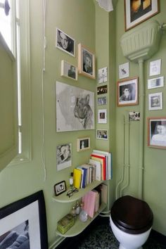 a bathroom with green walls and pictures on the wall, including a toilet in the corner