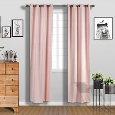 a pink curtain hanging on the side of a white wall next to a dresser and window