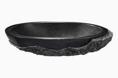 a black bowl sitting on top of a stone slab in front of a white background