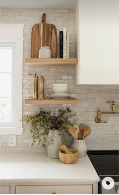 a kitchen with white counter tops and open shelving above the stove, along with wooden utensils