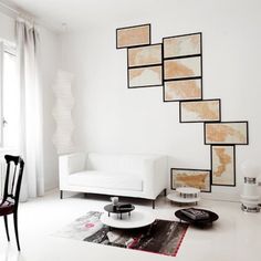 a living room with white furniture and pictures on the wall above it's stairs