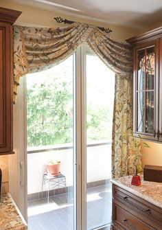 a kitchen with wooden cabinets and marble counter tops next to an open sliding glass door