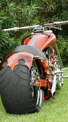 a red motorcycle parked on top of a lush green field