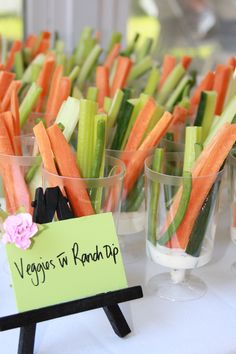 carrots and celery sticks are in small cups on a white tablecloth