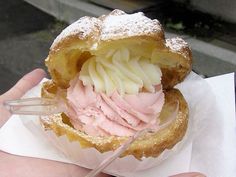 a hand holding a pastry with powdered sugar and icing in it's center