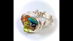 a silver ring with multicolored glass beads on the front and sides, sitting on a white surface