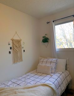 a bedroom with a bed, window and plant on the wall next to the windowsill