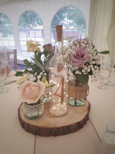 there are flowers in vases on the table with wine bottles and glasses next to each other