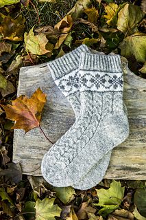 a pair of white socks sitting on top of a wooden bench next to autumn leaves