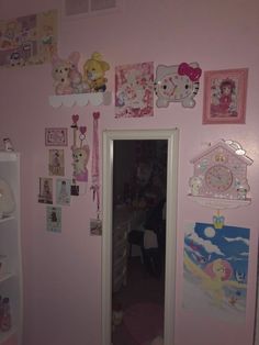 a pink room with hello kitty pictures on the wall and other items hanging on the walls