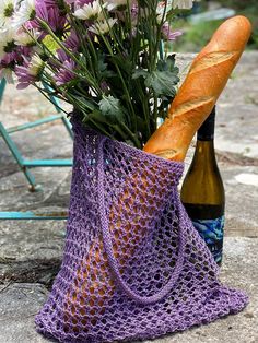 a purple bag with flowers in it and a bottle of wine on the ground next to it