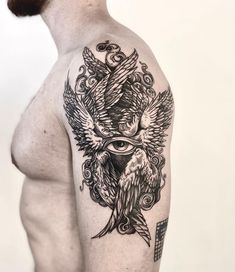 a man's upper half sleeve with an all seeing bird tattoo on his left arm