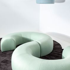 a large circular couch sitting on top of a black rug next to a white wall