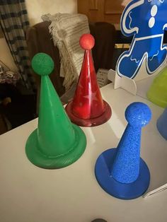 three different colored plastic hats sitting on top of a white table next to each other