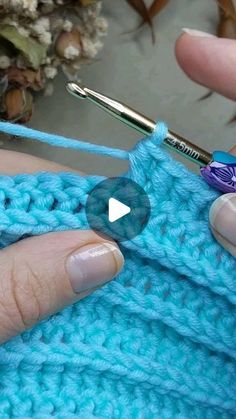 someone is crocheting the stitchs on their blue knitted blanket with a crochet hook