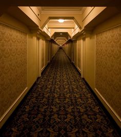 an empty hallway leading to another room in a hotel or other building with carpeted flooring