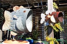 two metal fish sculptures hanging from the side of a building next to potted plants