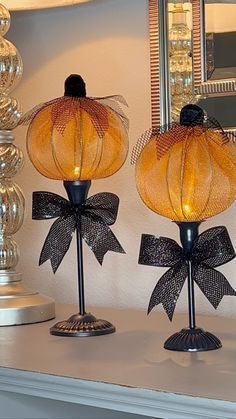 two lamps with bows on them sitting on a mantle