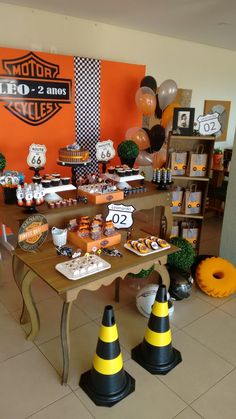 an orange and black motorcycle themed party with desserts on the table in front of it