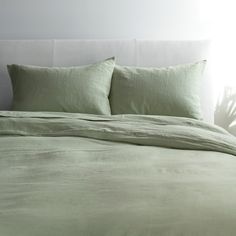 a bed with green sheets and pillows on it